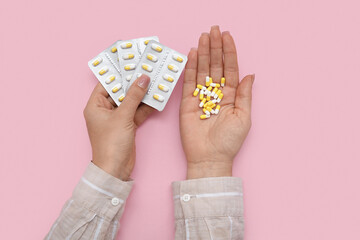 Wall Mural - Female hands with pills in blister packs on pink background