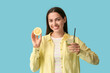 © Pixel-Shot - Beautiful young happy woman with lemon half and glass of fresh lemonade on blue background
