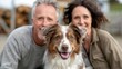 © LifeMedia - A joyful moment captured as a middle-aged couple smiles warmly while posing with their brown and white dog, symbolizing companionship and love in an outdoor setting.