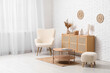 © Pixel-Shot - Modern chest of drawers with decor, armchair, coffee table and pouf near white brick wall in room