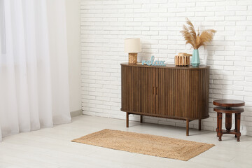 Wall Mural - Stylish chest of drawers with lamp, coffee table and wooden word RELAX near white brick wall in room