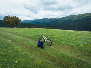 Wall Mural - Aerial view of woman riding mountain bike on flowering grassland mountain