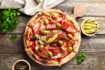 Tasty pizza and ingredients on wooden table, top view