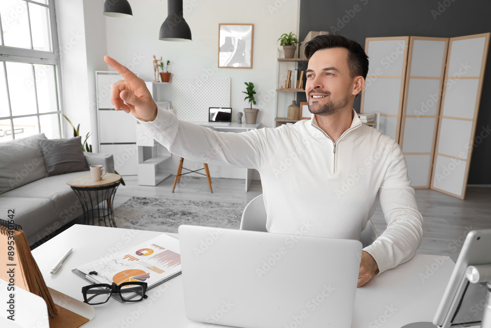 Young businessman using virtual screen at table in office
