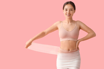 Sticker - Young Asian woman in anti-cellulite bandage on pink background. Body wrap procedure