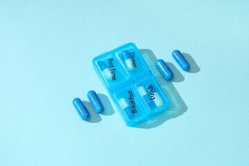 Wall Mural - Plastic container with pills on blue background. Top view