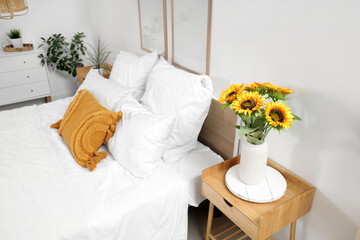 Poster - Interior of light bedroom with cozy bed and beautiful sunflowers on bedside table