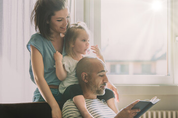 Young family enjoying time together reading a book