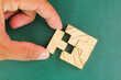 © Fauzi - hands complete a wooden puzzle. last missing piece, solutions and challenges concept