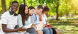 © Prostock-studio - Smiling African American Student Guy Studying Outdoors With His University Friends, Holding Smartphone And Smiling At Camera, Selective Focus
