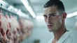 © Whitefeather - A man with a shaved head stands in front of a wall of hanging meat