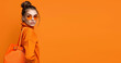 © Porechenskaya - Stylish fall winter fashion girl on orange background.