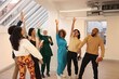 © Caia Image - Multiethnic group of smiling creative workers raising hands and cheering in modern office