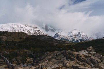 A mountain range covered in snow and clouds. The sky is cloudy and the mountains are covered in snow