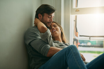 Wall Mural - Couple, happy and relax by window in house for comfort, love and bonding time together with trust and care. Man, woman and hug or cuddle in home for connection, relationship and support on weekend