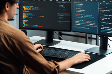 IT developer working online software development on pc monitors at modern home office on coding application screens, creating updated latest program firmware information version concept. Gusher.