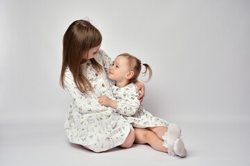 Wall Mural - A portrait of two sisters on a white background with copy space. Happy children having fun together.