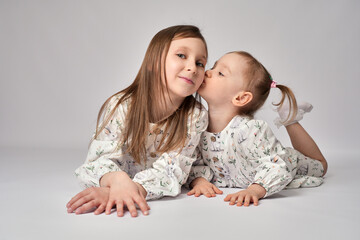 Wall Mural - A portrait of two sisters on a white background with copy space. Happy children having fun together.