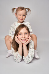 Wall Mural - A portrait of two sisters on a white background with copy space. Happy children having fun together.