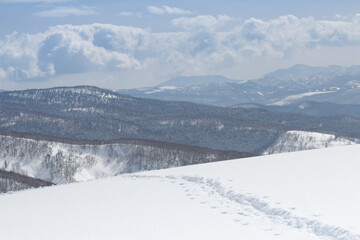 Wall Mural - line of footprints leading over snowy mountain ridge winter landscape in hokkaido japan