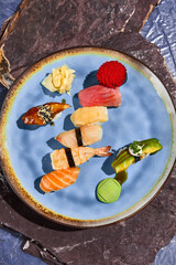 Wall Mural - Assorted Sushi Plate Featuring Salmon, Tuna, Shrimp, Eel, Perch, Scallop with Avocado on Blue Plate