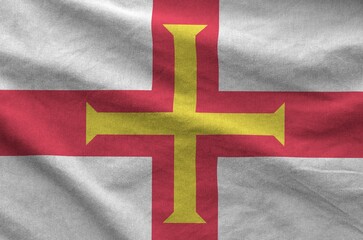 Wall Mural - Guernsey flag depicted on folded wavy fabric of old cloth close up