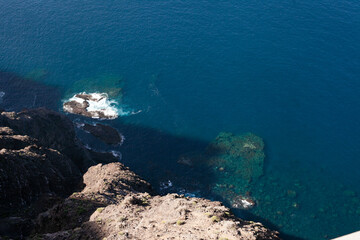 aerial view of blue sea or ocean and rocks, looking down from top of the cliff or mountain, horizontal and copy space