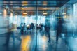 © Igor - Business meeting in a modern office with blurred figures visible through glass walls, conveying a collaborative work