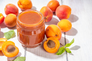 Sticker - Homemade sweet sour apricot chutney jam preserves with spices and raisins, in small jar, with fresh ripe apricots on white wooden table