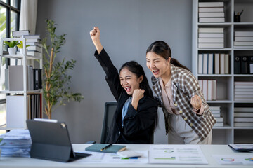 Two women are celebrating in a business office