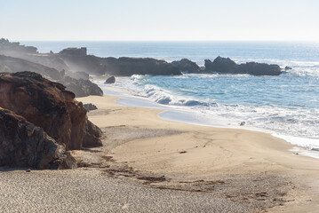 Enormous waves breaking on a deserted sandy beach along the rugged coast of central California on a sunny autumn day