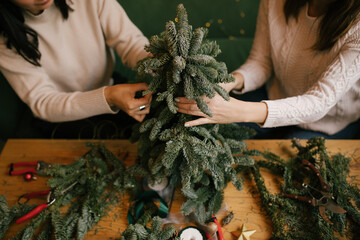 Wall Mural - Two women making Christmas tree using natural pine branches on a workshop.