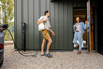 Man coming home with a shopping bag with vegetables, woman greets while standing at a doorway. Concept of happy family living