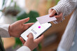 © Studio Marmellata - Two people using NFC technology to make a payment with their mobile phones One phone shows the payment amount, demonstrating a cashless transaction