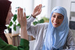 © Studio Marmellata - Three women in hijabs high-five each other in a modern office They are celebrating a success, highlighting teamwork and a positive work environment