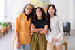 © Studio Marmellata - Three diverse women smile together in a bright modern office The women are dressed in colorful outfits and are standing close to each other showcasing their camaraderie and friendship