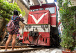 © milkovasa - An irresponsible tourist is photographing with mobile phone a arriving train in a tourist popular narrow street in Hanoi, Vietnam.