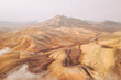 © AmazingAerialAgency - Aerial view of remote and barren mountains and hills with road and clouds, Mirador Astronomico de Sicasumbre, Fuerteventura, Spain.
