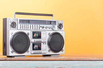 Wall Mural - boombox radio stereo cassette recorder on vintage wooden shelf front yellow background. retro old st