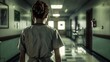 © Nattapol - A woman in a white uniform stands in a hospital hallway