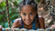 © JoxyAimages - A young girl with beautifully braided hair climbs up a rope in a lush forest, displaying determination and strength while enjoying an adventurous outdoor activity.