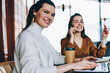 © BullRun - Portrait of smiling millennial female copywriter sitting at desktop with laptop device using cafeteria wifi, two female bloggers spending time together at coffee shop browsing internet on netbook