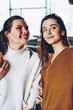 © BullRun - Positive smiling women making pictures on mobile front camera posing for photo indoors, successful hipster girls casual dressed taking images using modern smartphone device at university campus