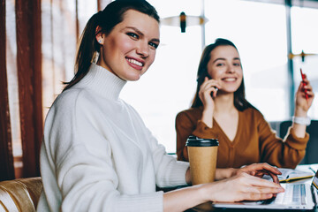 Wall Mural - portrait of smiling millennial female copywriter sitting at desktop with laptop device using cafeter