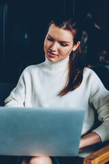 Wall Mural - Positive female student watching funny video with friend using laptop device connected to cafeteria wifi, two successful women browsing wireless internet for download file resting at cafeteria