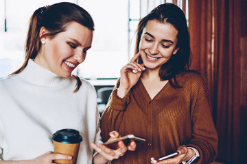 Wall Mural - cheerful female bloggers sharing information via bluetooth connection on smartphones, positive smili
