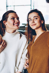 Wall Mural - positive smiling women making pictures on mobile front camera posing for photo indoors, successful h
