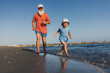 © sutulastock - Grandfather and Grandson Joyfully Running on the Beach