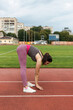 © O.Farion - A young sporty woman doing morning workout exercises, stretching, in the stadium