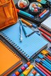 © Ihor - School supplies, including notebooks, pens, pencils, and markers, lay spread out on a gray surface